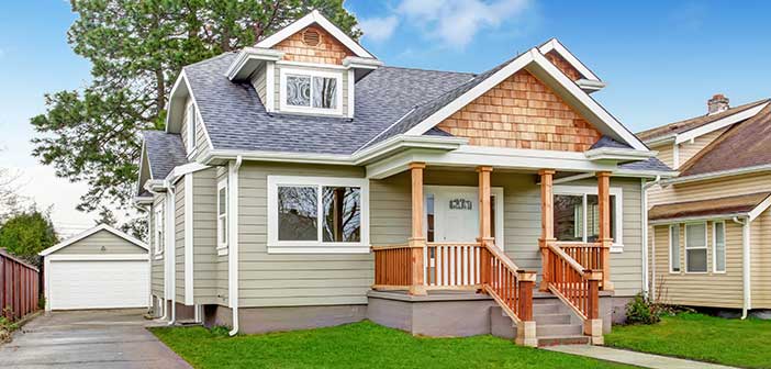 modest single family home green siding white trim two-car garage on grassy green lot