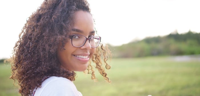 dark curly haired pretty woman in glasses smiling outdoors