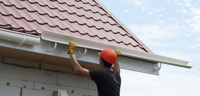 worker installs the gutter system on the roof