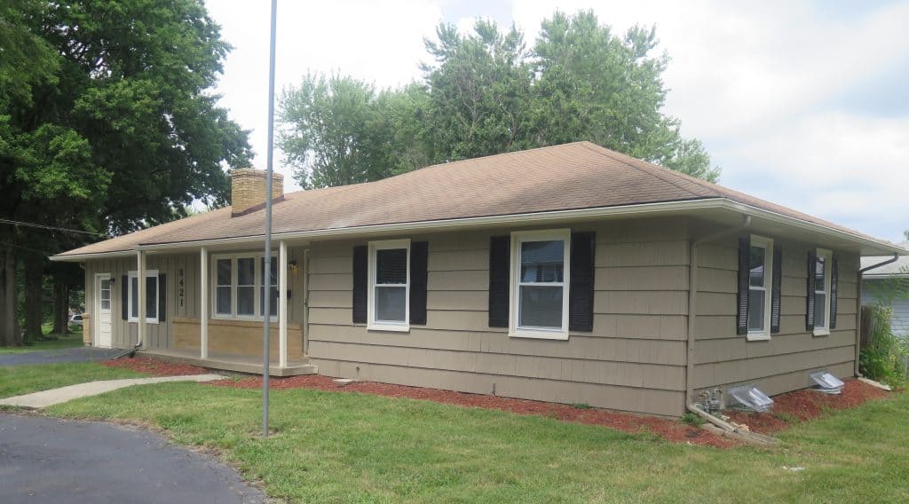 single-level home with tan siding and black shutters 