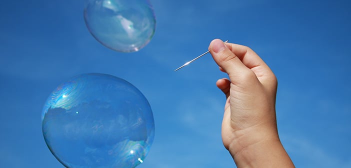 hand holding needle near bubbles set against blue sky background