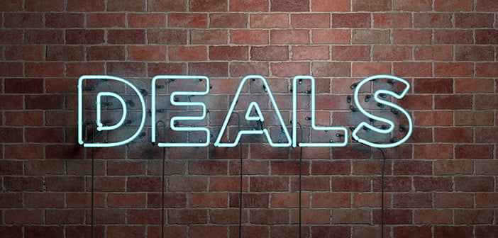 fluorescent neon sign reads deals on brick wall