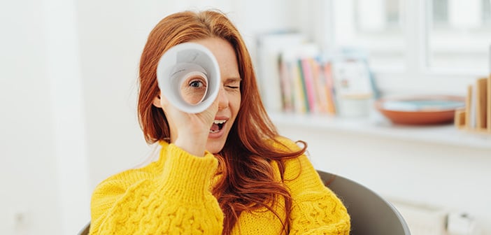 woman looking through rolled up paper suggesting focusing on one thing