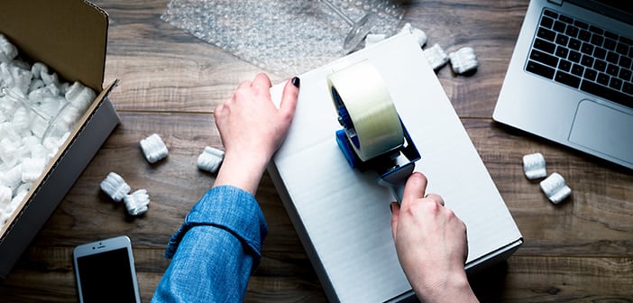 woman packing and sealing a moving box with tape