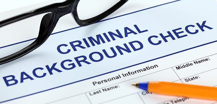 Criminal background check application form with glasses and ballpoint pen.