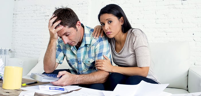 young sad couple at home living room couch calculating monthly expenses worried