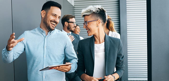 business people walking, talking and smiling in office hallway