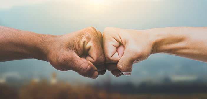 Man giving fist bump in sun rising nature background. power of teamwork concept. vintage tone