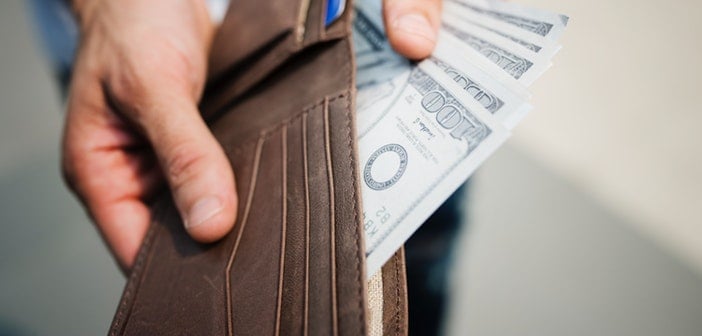 closeup of white male holding open wallet fanning out cash