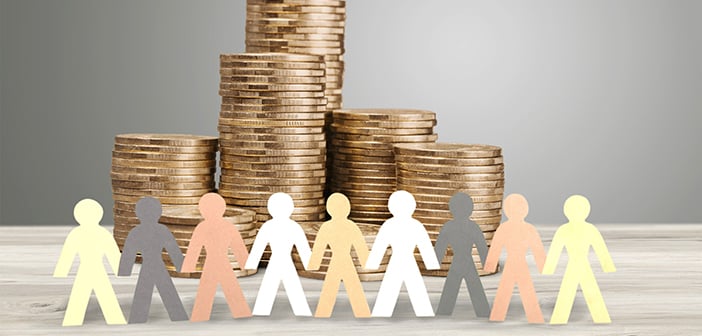 paper cutouts of people on multicolored paper positioned in front of several stacks of coins against a gray background