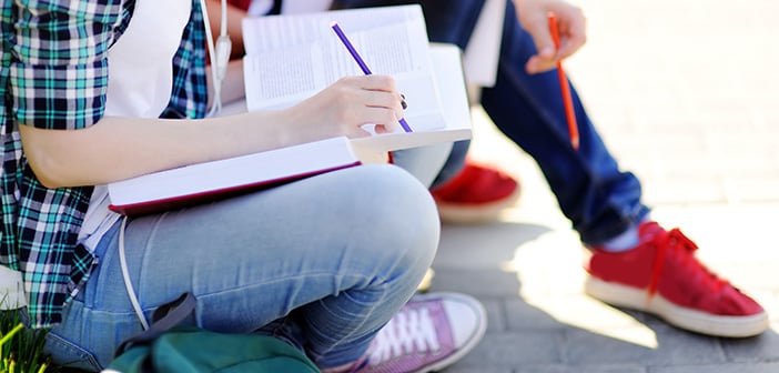 Close up photo of young happy students with books and notes outdoors. Smart young guy and girl in University campus. Learning and education for young people.