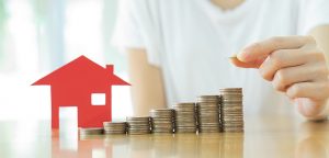 house cutout and coins stacks increasing in height in a row on table