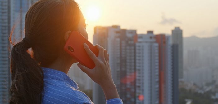 Woman talking on cellphone with the city background under sunlight