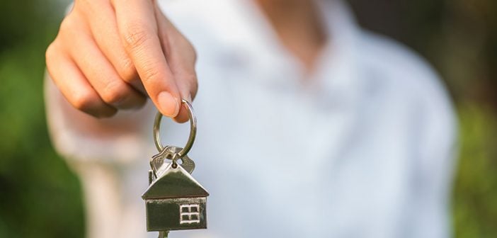 house key in woman hand and green leaves background