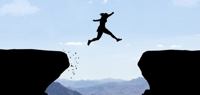 silhouette of woman leaping off one cliff aiming to land on another several feet away, conveying leap of faith