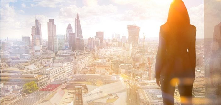 Young woman looking over the City of London at sun set.