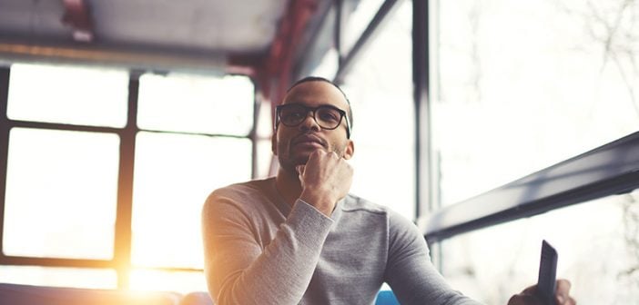 Pensive afro american handsome professional writer of popular articles in blog dressed in trendy outfit and glasses thinking over new story proofreading his script from notebook sitting in cafe