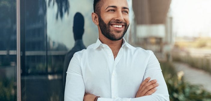 Portrait of a young confident smiling indian man with his arms crossed looking into the distance