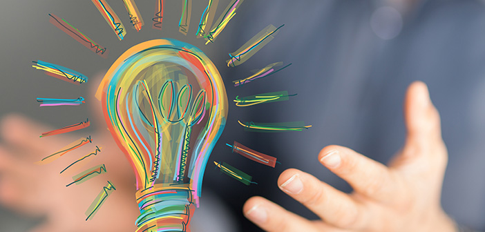 close up of man's hands hovering under colorful drawing of lightbulb