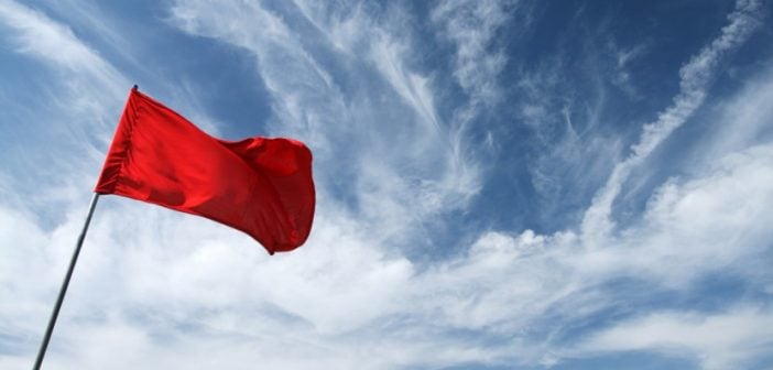 blue sky background with some clouds and red flag in foreground waving in wind