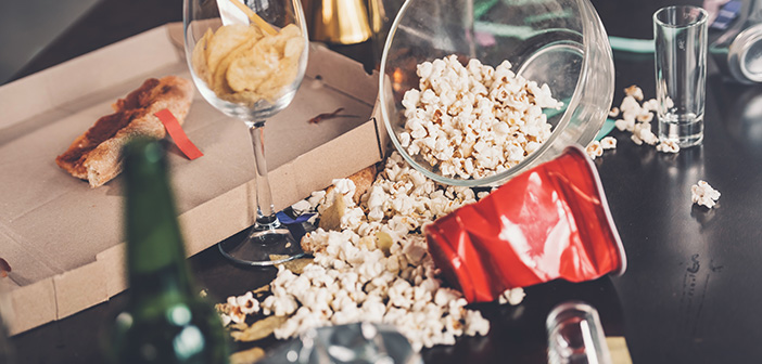 Close-up view of popcorn, glasses and trash on messy table after party