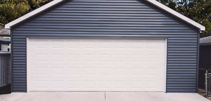 detached garage with new-looking slate blue siding white door and black roof