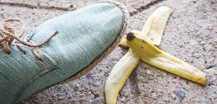 light turquoise canvas shoe about to step on banana peel on sidewalk
