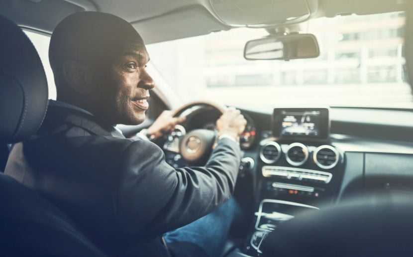 man driving luxury sedan looking out passenger window