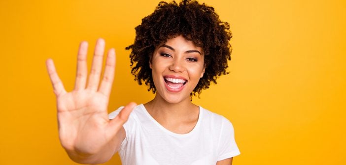 Close up photo beautiful amazed she her dark skin lady glad arms hands five fingers raised show countable uncountable things lesson wearing casual white t-shirt isolated yellow bright background.