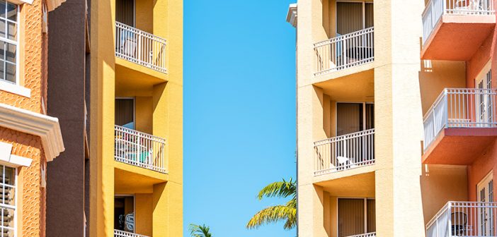 Colorful condos, condominiums colorful, orange yellow multicolored buildings facade exterior with windows, palm trees, mansion real estate property in Florida or Spain