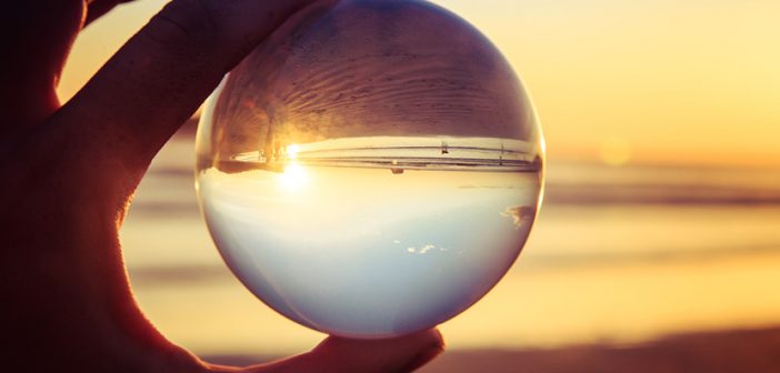 Landscape concept with crystal ball or esphere in hand during sunset on beach