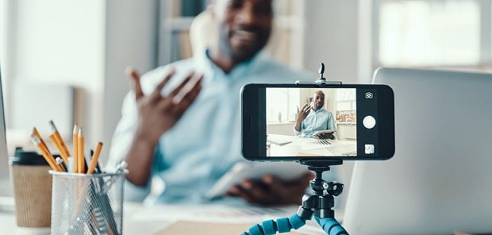 Handsome young African man in shirt telling something and smiling while making social media video