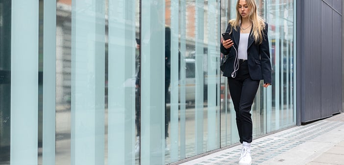 Teenage girl walking with mobile phone in hand and ear phones in