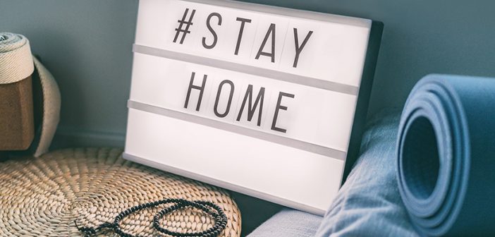 Coronavirus Yoga at home sign lightbox with text hashtag #STAYHOME glowing in light with exercise mat, cork blocks, strap meditation pillows. COVID-19 banner to promote self isolation staying at home.