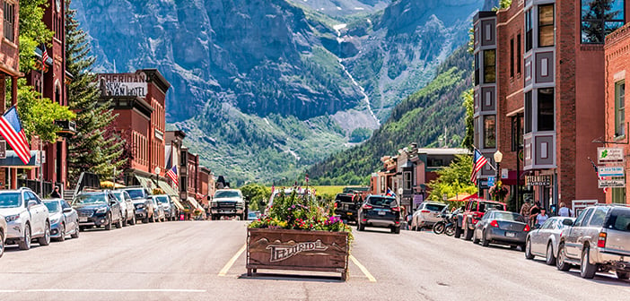 Telluride, Colorado - small town village in Colorado with sign for city and flowers by historic architecture on main street mountain view