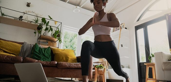 young mixed race female doing home workout or yoga from home, following an online workout on computer or online