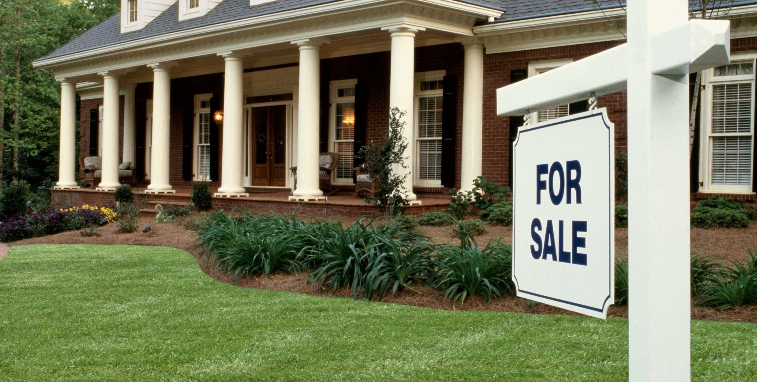 for sale sign in front of brick house