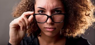 close up portrait of a very skeptical curly haired woman staring at your eyes straight