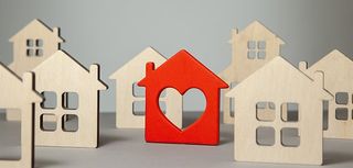 natural color wooden house cutouts with one painted red with a heart cutout added