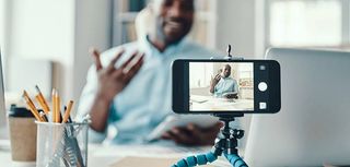 Handsome young African man in shirt telling something and smiling while making social media video