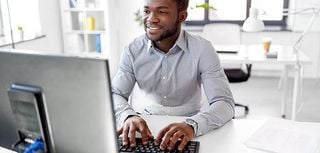 man sitting at desk working on a computer