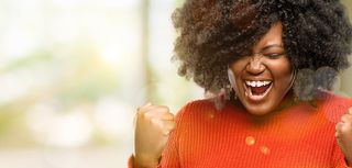 Beautiful african woman happy and excited celebrating victory expressing big success, power, energy and positive emotions. Celebrates new job joyful, outdoor