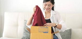 delivery, mail and people concept - smiling Asian woman opening cardboard box at home.