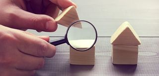 magnifying glass looking into wooden blocks shaped like houses