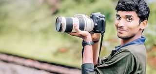 man in nature holding up SLR camera with telephoto lens