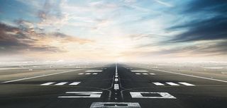 Empty asphalt airport runway with dramatic sky.