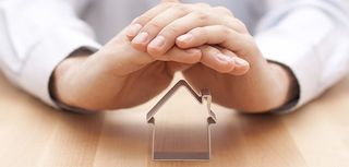 closeup of hands clasped shielding cookie cutter in shape of house