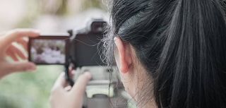 Student girl photographer learning attention take photo for hobby, camera on tripod at outdoor background in university