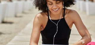 Pretty afro american woman listening audiobook on tablet smiling