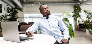 Man sitting in the office at the table making notes in a notebook